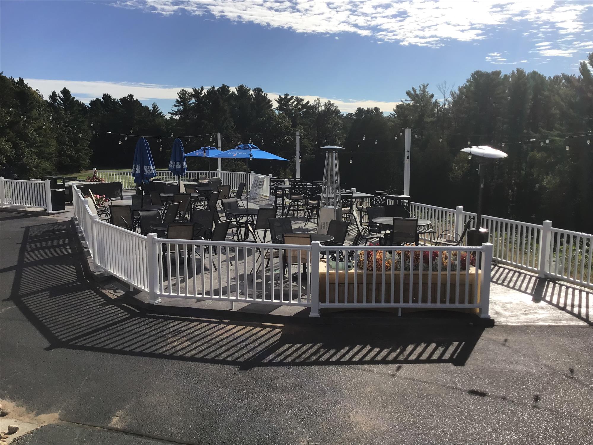 Outdoor patio with tables and chairs overlooking the course
