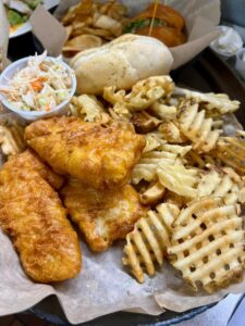 Breaded fish sticks with coleslaw, fries, and a bread roll