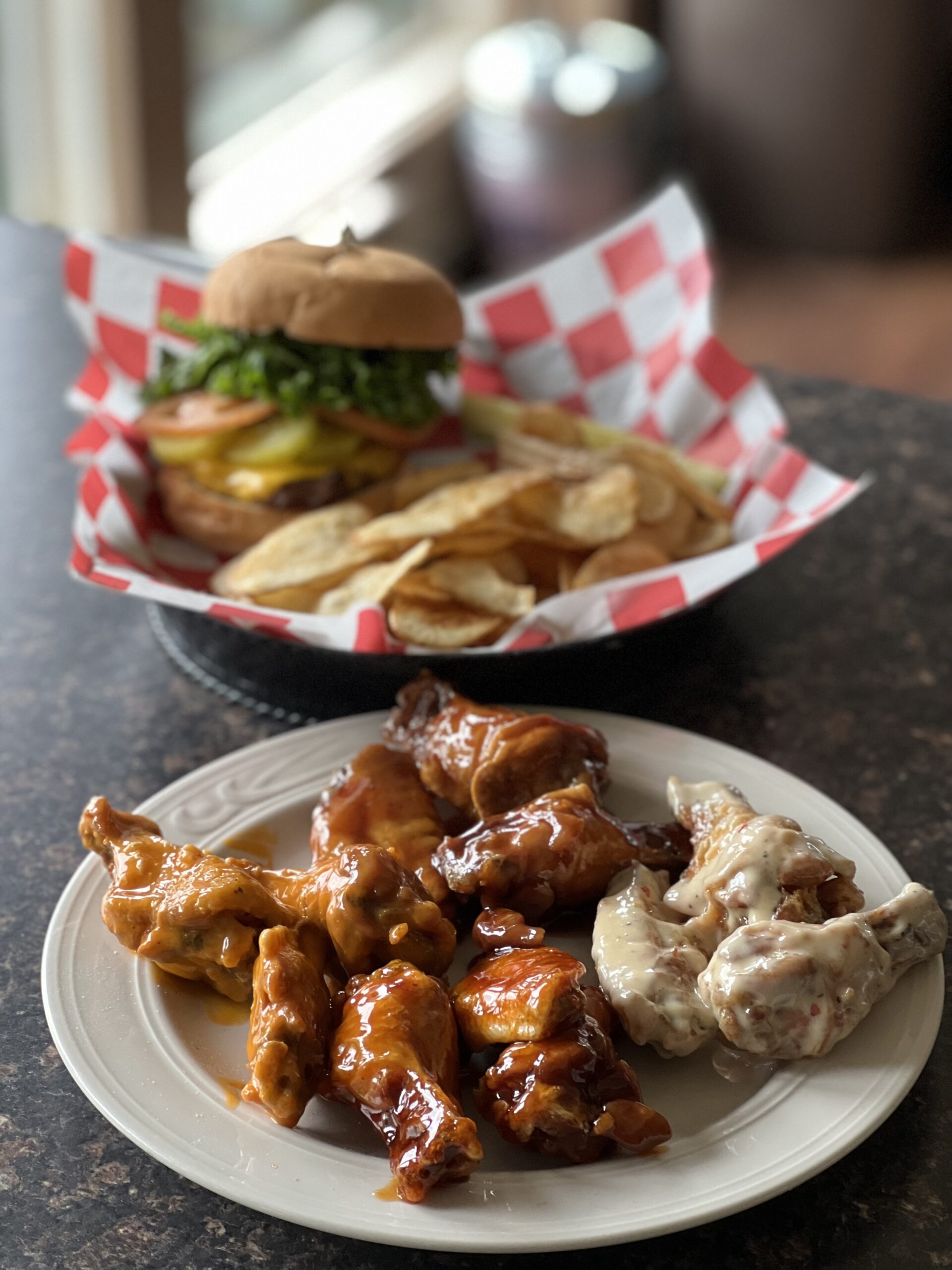 Plate of chicken wings and a burger with chips