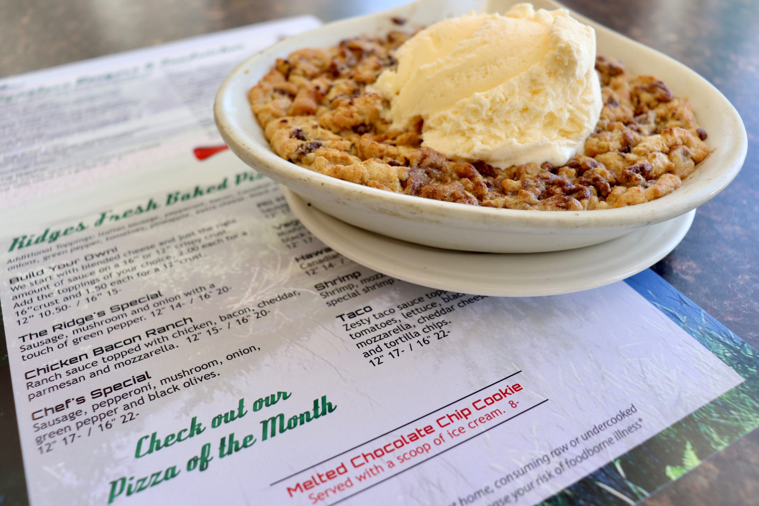 Melted chocolate chip cookie in a bowl topped with a scoop of ice cream