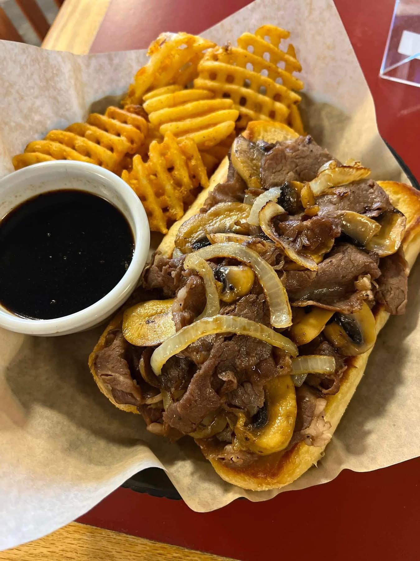 Steak sandwich topped with mozzarella, mushrooms, and onions