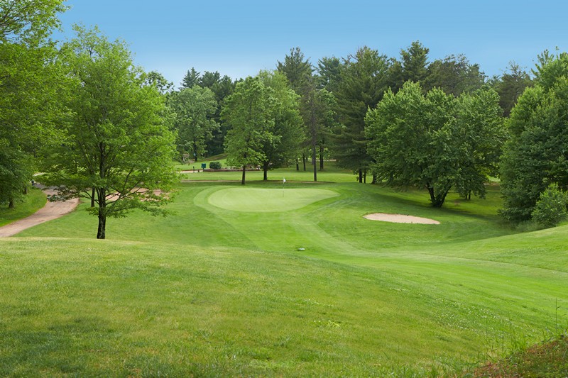 Putting green and sand trap surrounded by trees
