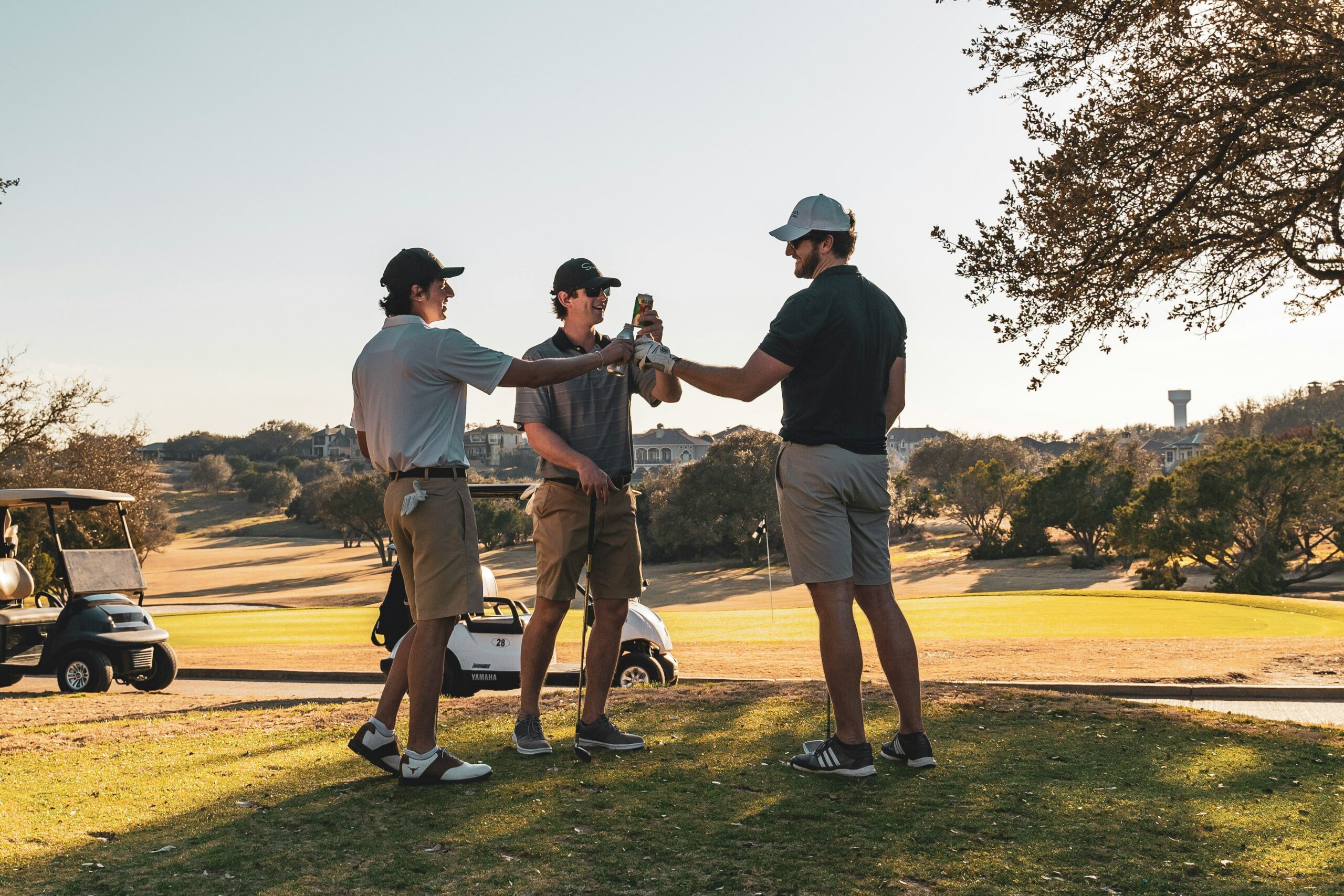 Three men on the golf course raising their drinks in a toast