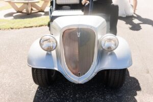 Front view of a classic white car with a vintage grille and round headlights