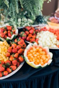 Fruit display featuring strawberries, cantaloupe balls, and pineapple chunks on platters