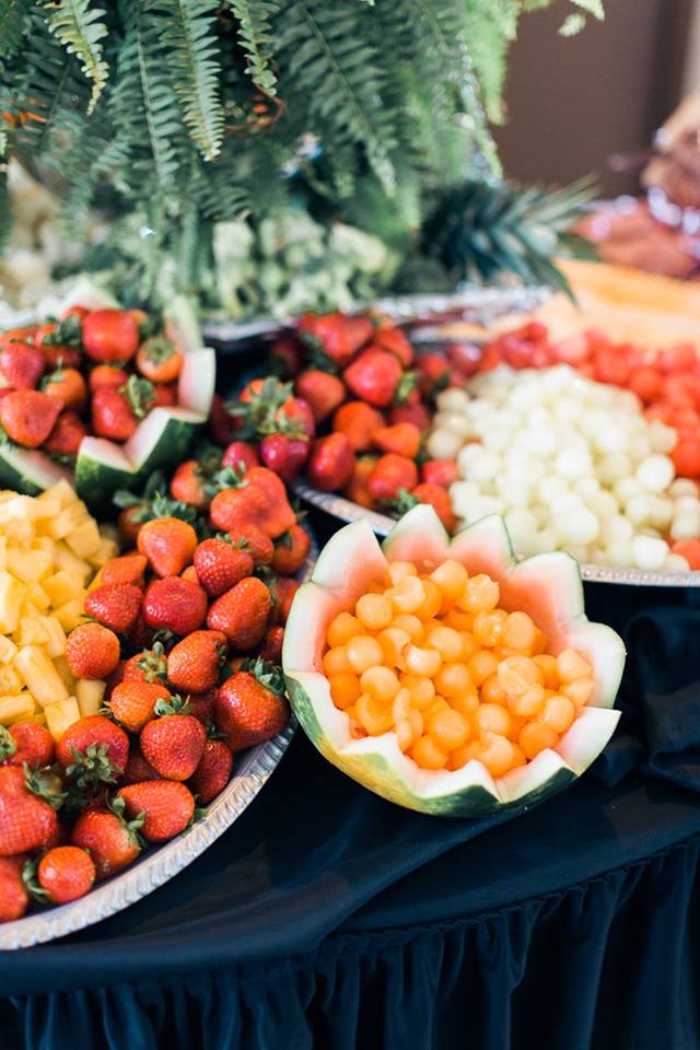 Fruit display featuring strawberries, cantaloupe balls, and pineapple chunks on platters