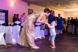 Woman in a gold dress and a young boy dancing together at a wedding