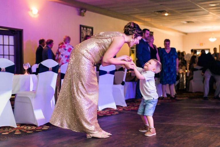 Woman in a gold dress and a young boy dancing together at a wedding
