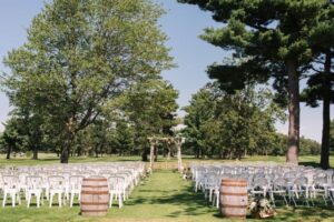 Outdoor wedding ceremony setup, featuring rows of chairs and a floral archway