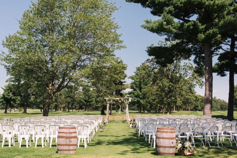 Outdoor wedding ceremony setup, featuring rows of chairs and a floral archway