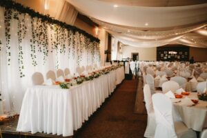 Elegant wedding reception hall with draped ceilings, decorated tables, and chairs