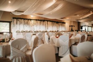Elegant wedding reception hall with draped ceilings, decorated tables, and chairs