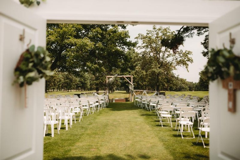 Outdoor wedding setup featuring rows of chairs and a wooden arch